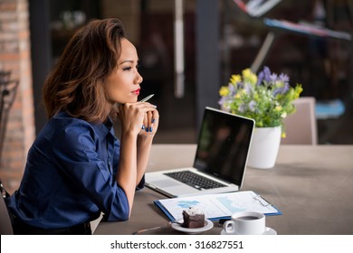 Vietnamese business lady pondering over ideas for new business project - Powered by Shutterstock