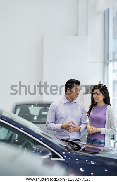 Vietnamese couple\
choosing nice car in\
showroom