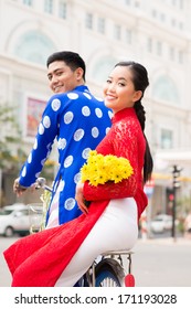 Vietnamese couple in traditional clothes cycling in the city