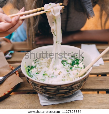 Vietnamese cuisine soup Pho Ga with chicken, noodles, fresh herbs and sauce in a bowl.