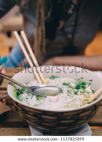 Vietnamese cuisine soup Pho Ga with chicken, noodles, fresh herbs and sauce in a bowl.