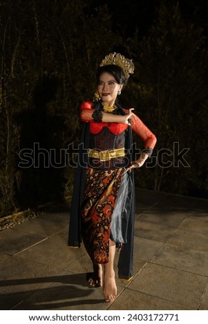 a Vietnamese dancer wearing a red costume and gold jewelry on stage at night