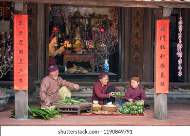 Vietnamese family members making Banh Chung together on old-styled house yard. Chung cake is a very well-known dish that could never miss on the altar, and family meal of Vietnamese during Tet holiday
