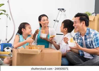 Vietnamese Family Sitting On The Floor And Eating Noodles And Pizza In Their New House