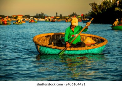 Vietnamese fisherman on coconut basket boat at Ba Tran: Hoi An Water Coconut Forest near Hoi An, Vietnam. Sunset scene with tourists in background - Powered by Shutterstock