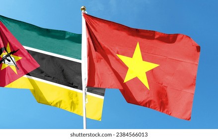Vietnamese flag and Mozambican flag flutter under cloudy sky. fly in the sky