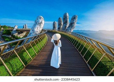 Vietnamese girl with traditional dress (ao dai) on Golden bridge at the top of the Ba Na Hills, Vietnam - Shutterstock ID 2338445623