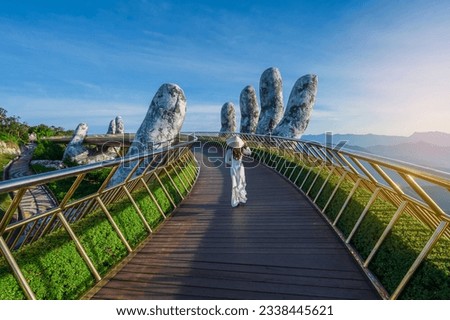 Vietnamese girl with traditional dress (ao dai) on Golden bridge at the top of the Ba Na Hills, Vietnam