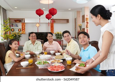 Vietnamese happy big family celebrating Tet together; couplets with best wishes for coming year in the background