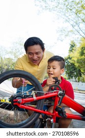 Vietnamese Man Showing His Son Spinning Wheel Of A Bicycle