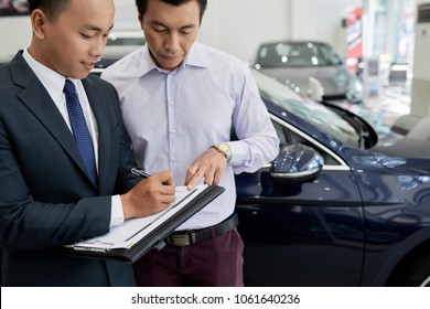 Vietnamese Man Signing Up For Test Drive At Car Dealer