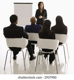 Vietnamese Mid-adult Woman Standing In Front Of Business Group Leading Presentation.