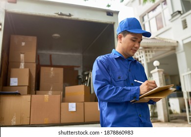 Vietnamese moving house company courier standing at delivery truck full of boxes and filling information in contract