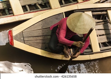 Vietnamese Old Woman With Typical Conical Hat In A Wood Boat. Top View