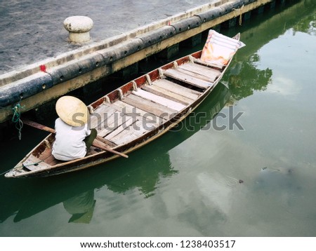 Vietnamese paddler waiting for tourists in wood traditional boat. Hoi An, Vientnam