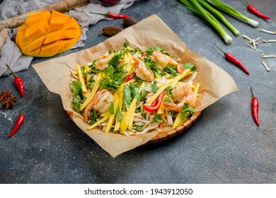 Vietnamese shrimp salad with greens amd mango on beautiful dark stone table