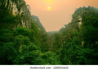 Vietnamese tropical nature (tropical winter). Forests and rocky cliffs of the mountains - narrow canyon, savage scenery. The setting of the foggy sun - Shutterstock ID 2200531653