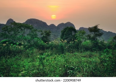 Vietnamese tropical nature (tropical winter). Forests and shrubs of the foothills, rocky cliffs of the mountains. The setting of the foggy sun - Shutterstock ID 2200908749