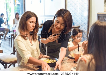 Vietnamese waitress cleaning table for customers in cafe showing vietnamese culture and politness