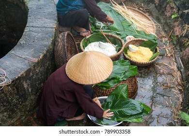 Vietnamese woman preparing to make Chung Cake, the Vietnamese lunar new year Tet food outdoor by old well and pond