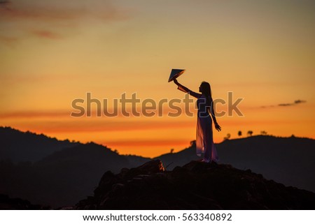 Vietnamese woman stand alone show Vietnam hat in her hand at twilight time