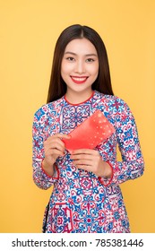 Vietnamese woman traditional festival costume Ao Dai, holding red money pockets.