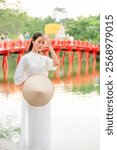 A Vietnamese woman in a traditional white dress at a landmark in Hanoi, the capital of Vietnam.