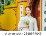 A Vietnamese woman in a traditional white dress at a landmark in Hanoi, the capital of Vietnam.