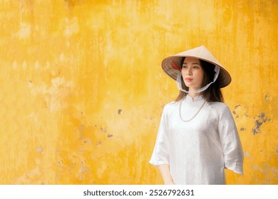 A Vietnamese woman in a traditional white dress at a landmark in Hanoi, the capital of Vietnam. - Powered by Shutterstock