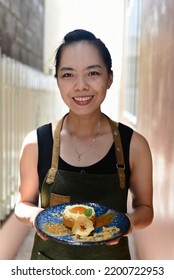 Vietnamese Woman Waitress In Apron Holding Apple Tart On A Blue Plate