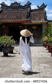 Vietnamese Woman wearing a Ao-Dai costume in front of a Temple
