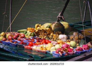 Vietnamese women people rowing vintage retro wood boat for sale local food fruit at floating fishing village bazaar market at Halong or Ha Long Bay UNESCO World Natural Heritage Site in Hanoi, Vietnam