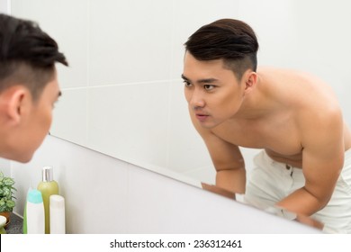 Vietnamese Young Man Looking At Himself In The Bathroom Mirror