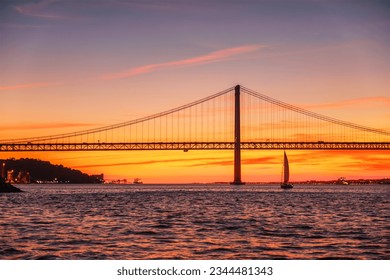 View of 25 de Abril Bridge famous tourist landmark of Lisbon connecting Lisboa and Almada over Tagus river with tourist yacht silhouette at sunset. Lisbon, Portugal - Powered by Shutterstock