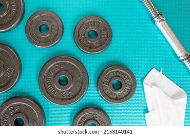 View From Above Of 2.5lb  5lb Barbells, White Sweat Towel And Weight Bar On A Blue Mat Green Exercise Mat