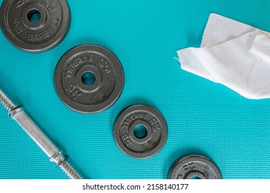 View From Above Of 2.5lb And 5lb Barbells, White Sweat Towel And Weight Bar On A Blue Mat Green Exercise Mat