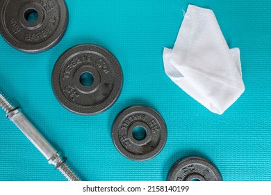 View From Above Of 2.5lb And 5lb Barbells, White Sweat Towel And Weight Bar On A Blue Mat Green Exercise Mat