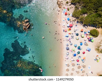 View From Above, Aerial View Of An Emerald And Transparent Mediterranean Sea With A White Beach Full Of Colored Beach Umbrellas And Tourists Who Relax And Swim. Costa Smeralda, Sardinia, Italy.