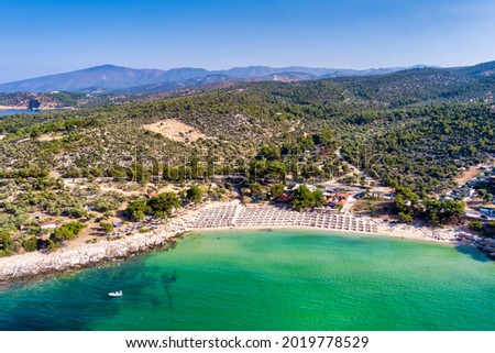 View from above, aerial view of an emerald and transparent Mediterranean sea with a white beach full of beach umbrellas and tourists who relax and swim. Psili Ammos, Thassos island, Greece.