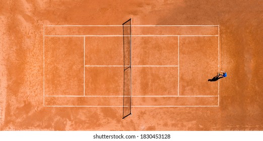 View From Above, Aerial View Of A Person Playing Tennis On A Clay Court During The Coronavirus (Covid-19) Outbreak. 