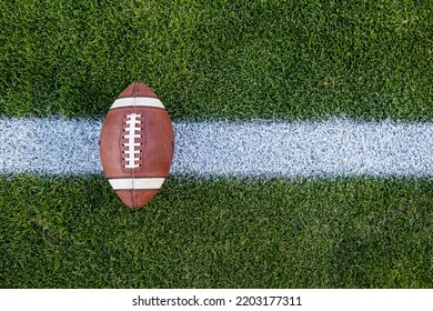 View From Above Of An American Football Sitting On A Grass Football Field On The Yard Line. Generic Sports Image	