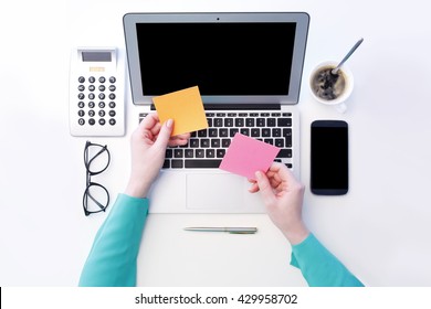 View from above of businesswoman sitting at her laptop and holding in her hand sticky notes while working online. Isolated on white background. - Powered by Shutterstock