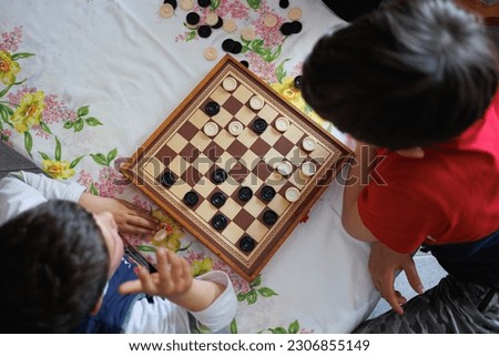 View from Above of a Checkers Game Board and two Children playing Checkers.
