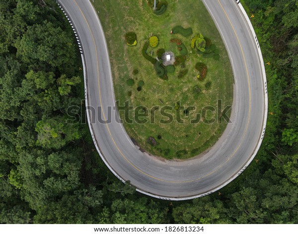 View from above of a curved winding road trough the\
mountains at Ping Ngu curve road, Sakon Nakhon Province,\
Thailand.taken from a drone   \
