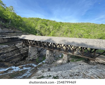 View from Above Dogwood Canyon of a Covered Wooden Bridge Over Rushing Water in the Ozark Mountains with Lush Green Trees - Powered by Shutterstock