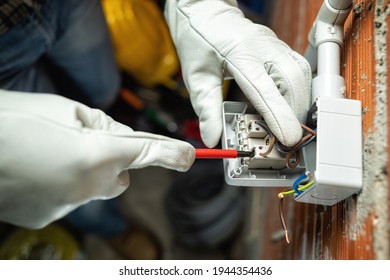 View from above. Electrician worker at work with a screwdriver fixes the cable in the terminal of the switch of a residential electrical system. Working safely with protective gloves. Industry. 