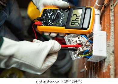 View from above  Electrician worker at work and the tester measures the voltage in switch residential electrical system  Working safely and protective gloves  Construction industry 