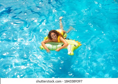 View from above of happy little girl swim on inflatable green matrass