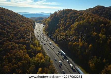 View from above of I-40 freeway in North Carolina heading to Asheville through Appalachian mountains in golden fall season with fast driving trucks and cars. Interstate transportation concept