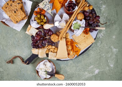 A view from above of a large round Charcuterie Board and glasses of white wine on a green table